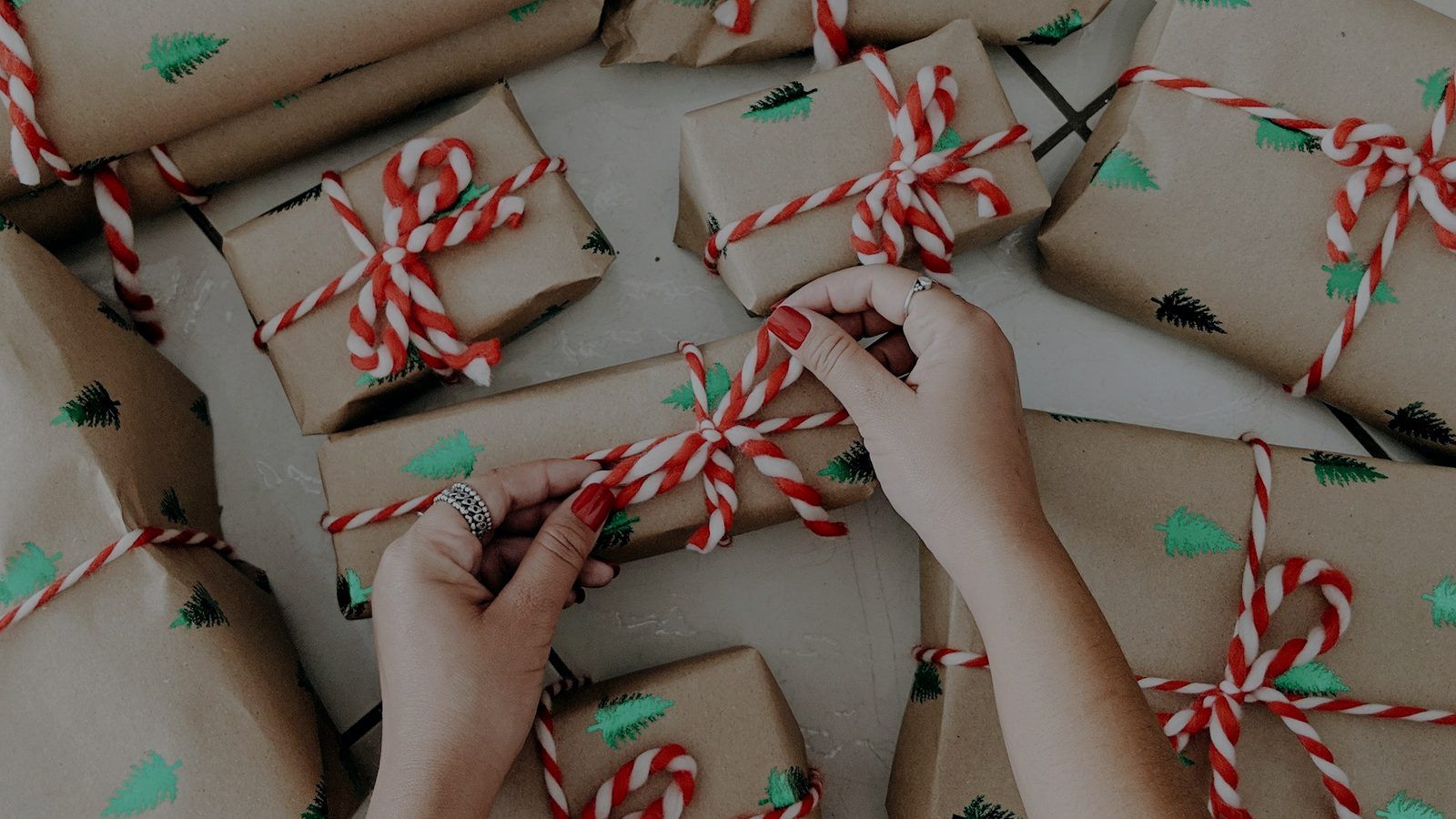 Mani che chiudono pacchetti regalo in carta da pacchi con nastri a righe rosse e bianche