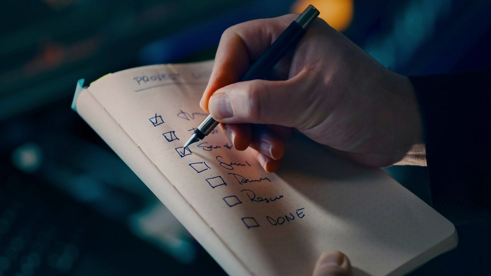 Una mano spunta a penna le voci di una lista su un quaderno