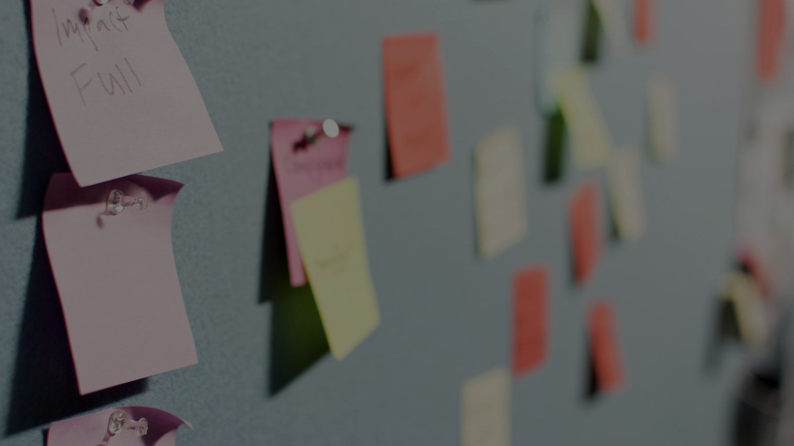 Post-it colorati appuntati su una bacheca grigia
